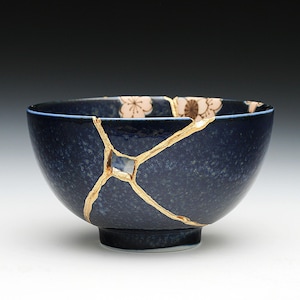 May include: A blue ceramic bowl with gold cracks and a floral design. The bowl is a traditional Japanese kintsugi style.