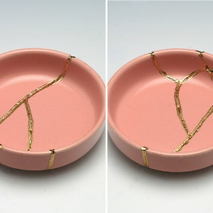 May include: Two pink ceramic bowls with gold crackle lines. The bowls are round and shallow.