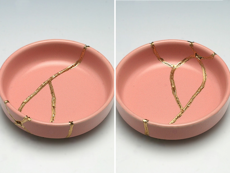 May include: Two pink ceramic bowls with gold crackle lines. The bowls are round and shallow.