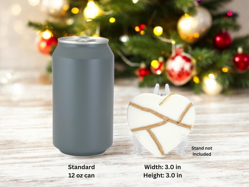 Peut inclure: Une d&eacute;coration en forme de c&oelig;ur blanche avec des accents dor&eacute;s, mesurant 7,6 cm de largeur et de hauteur. Une canette standard de 355 ml est pr&eacute;sent&eacute;e &agrave; titre de comparaison de taille. Le support n'est pas inclus.