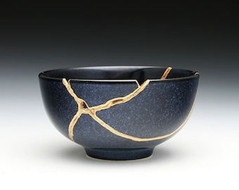 May include: A dark blue ceramic bowl with gold cracks. The bowl is a traditional Japanese style.