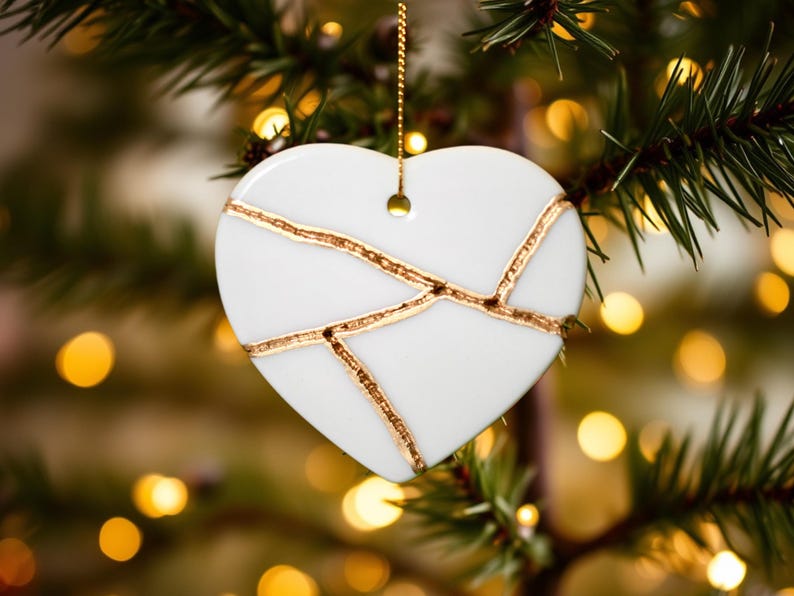 Peut inclure: Ornement de No&euml;l en forme de c&oelig;ur en c&eacute;ramique blanche avec un motif craquel&eacute; dor&eacute;. L'ornement est suspendu &agrave; un sapin de No&euml;l.