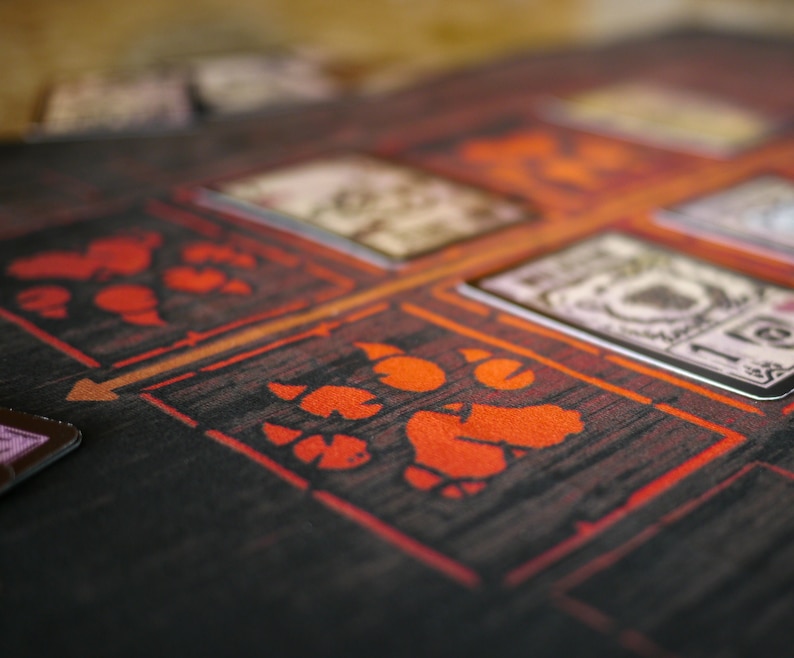 May include: A close-up of a dark wooden game board with red and orange symbols. The board has a grid pattern and features several cards with text and images.