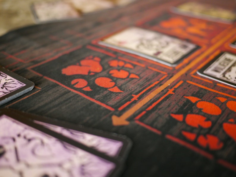May include: A close-up of a board game with red paw prints and a card with the word "VILLAGER" printed on it.