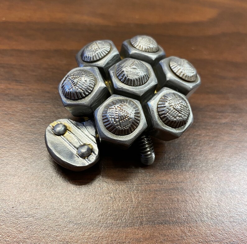May include: A silver metal sculpture of a turtle made from nuts and bolts.