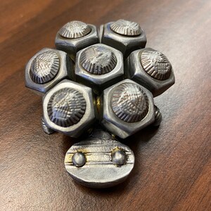 May include: A small metal turtle sculpture made from nuts and bolts. The turtle is silver with a gold accent on the head.
