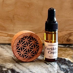 May include: A wooden diffuser with a geometric design and a small bottle of "Caribbe Cruise" diffuser oil. The bottle is 5 ml or 0.17 fl oz.