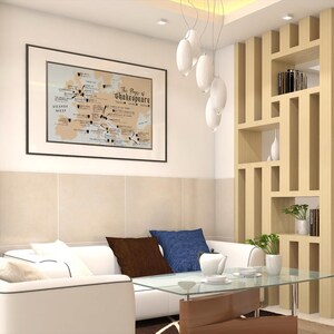 May include: A white sectional sofa with brown and blue throw pillows sits in a living room with a wooden bookshelf and a framed map of Shakespeare's plays on the wall.