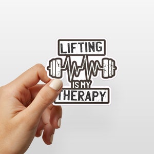 May include: A white sticker with black text and a graphic of a barbell with a heartbeat line. The text reads "Lifting is my therapy."