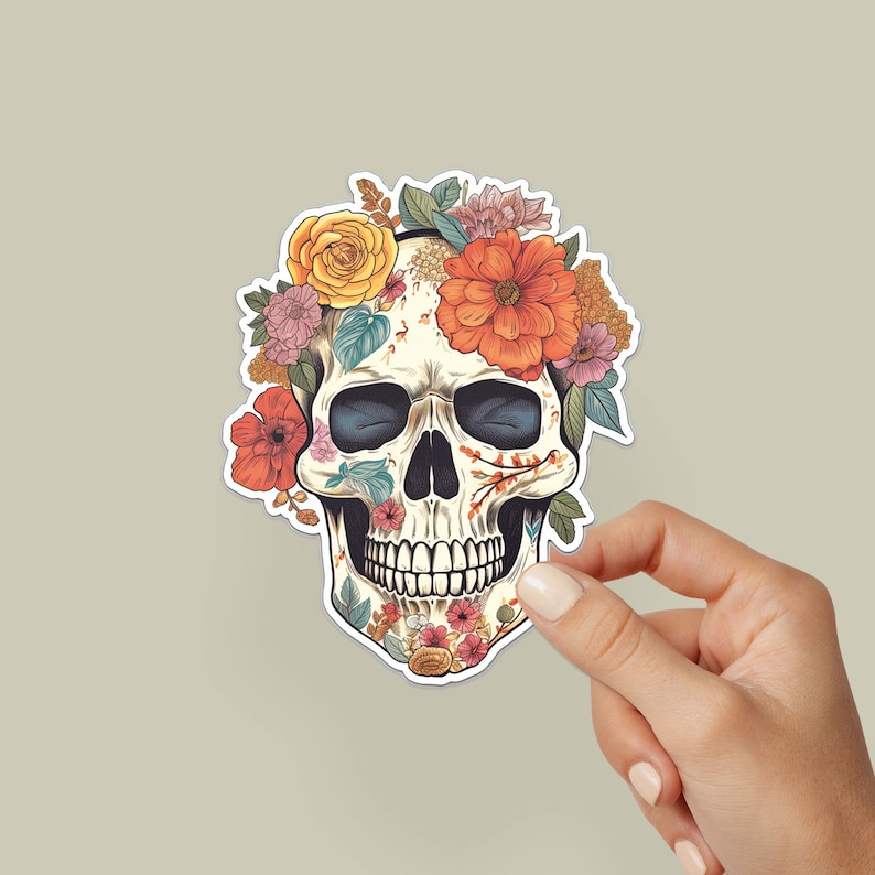 May include: A white sugar skull with floral details, including red, orange, yellow, and pink flowers. The skull is surrounded by a wreath of flowers.