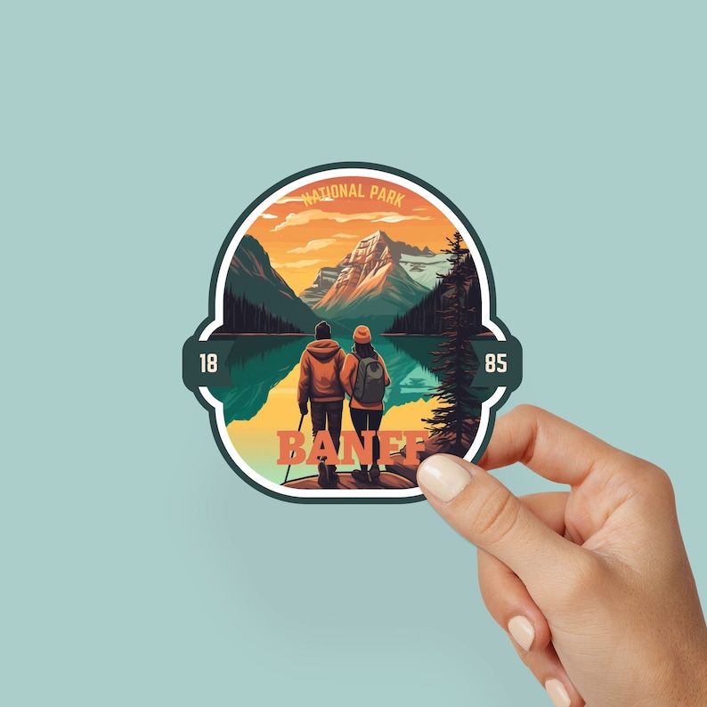 May include: A green and orange sticker with a mountain scene and a couple hiking. The sticker says "National Park" and "Banff" with the numbers "18" and "85" on either side.