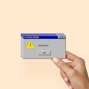 May include: A blue and gray computer error message with a yellow exclamation point and the text "SYSTEM ERROR" and "DEHYDRATED". The message has a blue "OK" button.
