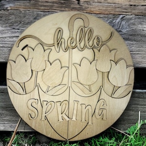 May include: A round wooden sign with the words "hello SPRING" cut out. The sign features a tulip design and an umbrella shape. The sign is made of light-colored wood and is suitable for spring decor.
