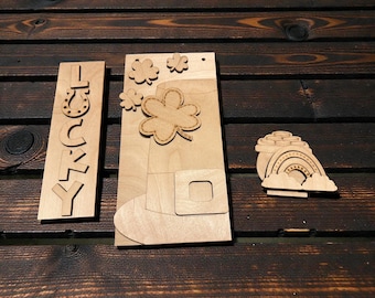 May include: Wooden St. Patrick's Day decorations. Includes a vertical sign with the word "Lucky", a leprechaun hat with shamrocks, and a pot of gold with a rainbow. The items are made of light-colored wood and are displayed on a dark wood surface.