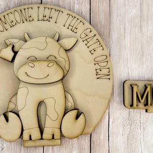 May include: Wooden sign with a cow cutout and the text "Live like someone left the gate open" and a separate wooden sign with the text "MOOO".