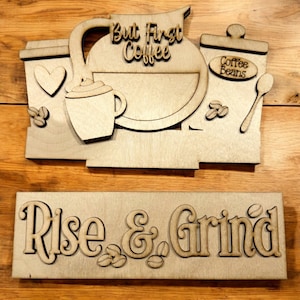 May include: Wooden sign with the text "But First Coffee" and a coffee pot, coffee cup, and coffee beans. A second wooden sign below reads "Rise & Grind" with coffee beans.