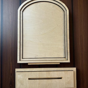 May include: A wooden, unfinished mailbox with an arched top and a rectangular base. The mailbox is made of light-colored wood with black trim and a slot for mail. The design is simple and modern.