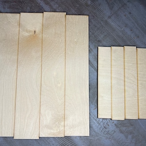 May include: A set of eight wooden strips, arranged in two groups. The larger group has five strips, while the smaller group has three. All strips are light brown and have a smooth, natural finish.