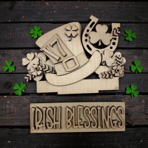 May include: Wooden St. Patrick's Day decoration featuring a leprechaun hat, horseshoe, and shamrocks. The hat has the number 17 on it. The words "IRISH BLESSINGS" are displayed below the hat. Green shamrocks are scattered around the wooden decoration.