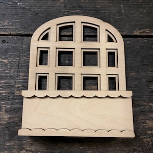 May include: A wooden window-shaped craft piece with an arched top and multiple square and rectangular openings. The bottom features a scalloped edge, and the wood has a natural, unfinished appearance. Ideal for DIY projects and home decor.