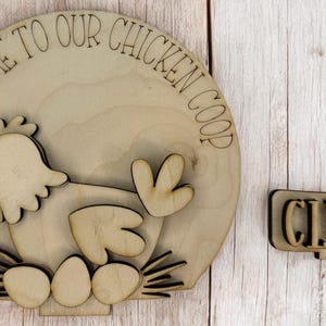 May include: Wooden sign with the text "Welcome to our Chicken Coop" and a cutout of a chicken with eggs. A separate wooden sign says "CLUCK".
