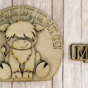 May include: Wooden sign with a cartoon highland cow and the text "Live like someone left the gate open". A separate wooden sign says "MOO".