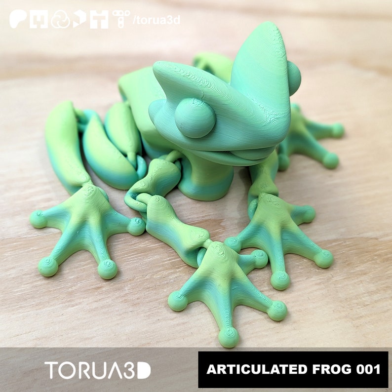 May include: A green and yellow articulated frog figurine with a textured surface. The frog is posed in a sitting position with its legs outstretched. The figurine is labelled "ARTICULATED FROG 001".