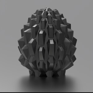 K&ouml;nnte beinhalten: Ein schwarzes, geometrisches, eif&ouml;rmiges Objekt mit einer strukturierten Oberfl&auml;che. Das Objekt besteht aus vielen kleinen, spitzen Formen, die an Schuppen erinnern.
