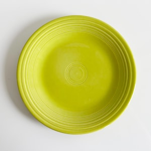 May include: A bright green ceramic dinner plate with a concentric circle design.