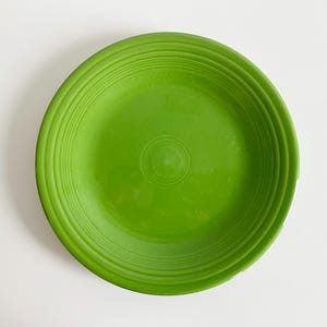 May include: A bright green ceramic dinner plate with a concentric circle design.