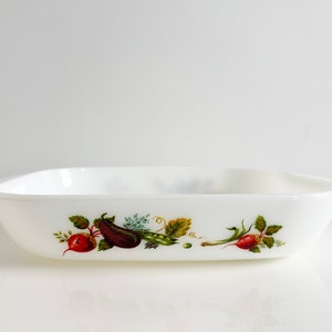 May include: White rectangular baking dish with a green, brown, and red vegetable design. The design features an eggplant, peas, and radishes.