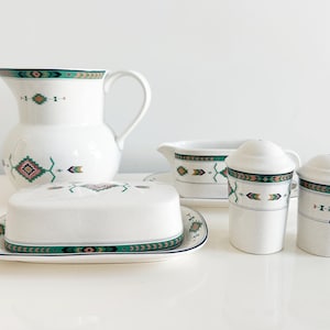 May include: A white ceramic dinnerware set with a Southwestern design. The set includes a pitcher, butter dish, gravy boat, and salt and pepper shakers. The design features geometric patterns in teal, green, and pink.