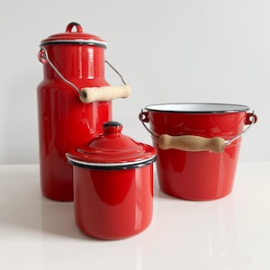 May include: Three red enamelware kitchen containers with white rims and wooden handles. The containers include a tall milk jug, a small jar with a lid, and a bucket.