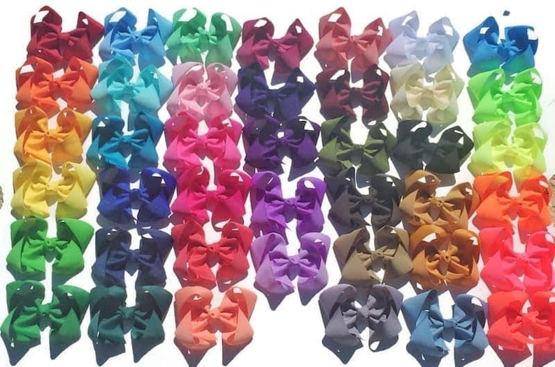 May include: A collection of colorful hair bows in various shades, including red, orange, yellow, green, blue, purple, and pink. The bows are arranged closely together, showcasing a wide array of hues and styles, perfect for accessorizing.