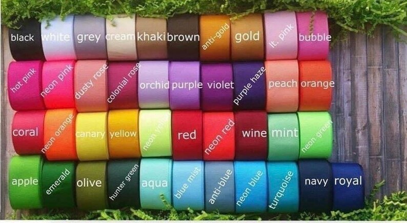 May include: A collection of colorful ribbon spools in various shades, including black, white, grey, and vibrant hues like hot pink, neon orange, and navy royal. Each spool is labeled with its color name.