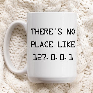 May include: White ceramic mug with black text that reads "There's no place like 127.0.0.1".
