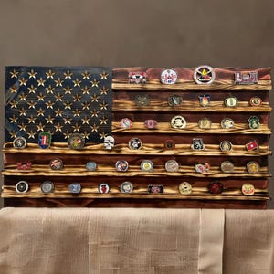May include: A wooden American flag display with shelves for holding challenge coins. The flag is painted in red, white, and blue with gold stars. The shelves are stained a dark brown color.