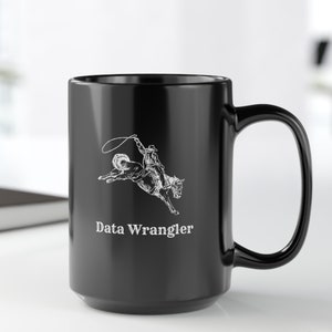 May include: Black ceramic mug with a white graphic of a cowboy riding a bucking horse. The text "Data Wrangler" is printed below the graphic.