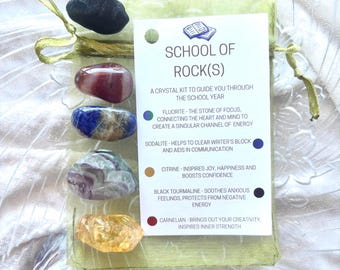 Pode incluir: Uma bolsa verde contendo cinco cristais: preto, vermelho, azul, verde e amarelo. Um cartão branco dentro da bolsa diz "School of Rock(s)" e lista diferentes tipos de cristais e suas propriedades.