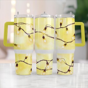 May include: Three yellow stainless steel tumblers with a design of white string lights on a yellow background. The tumblers have yellow lids and yellow handles.