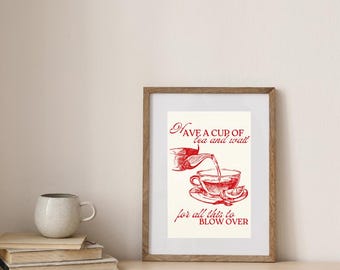 May include: A framed print with a red illustration of tea being poured into a teacup, with the text "Have a cup of tea and wait for all this to blow over." The print is in a wooden frame and sits on a wooden surface.