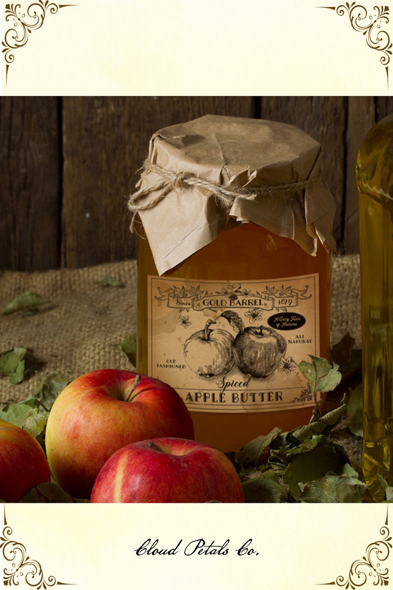 May include: A jar of spiced apple butter with a vintage label featuring apple illustrations. The jar is sealed with brown paper and twine, surrounded by red apples and green leaves. The label reads "Gold Barrel 1879".
