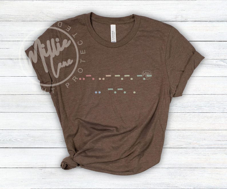 May include: A brown t-shirt with rolled-up sleeves. The shirt features a Morse code design in various colors across the chest. The brand name "Millie Lane" is printed on the upper left side of the shirt.