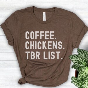 May include: A brown t-shirt with the text "COFFEE. CHICKENS. TBR LIST." printed in white.