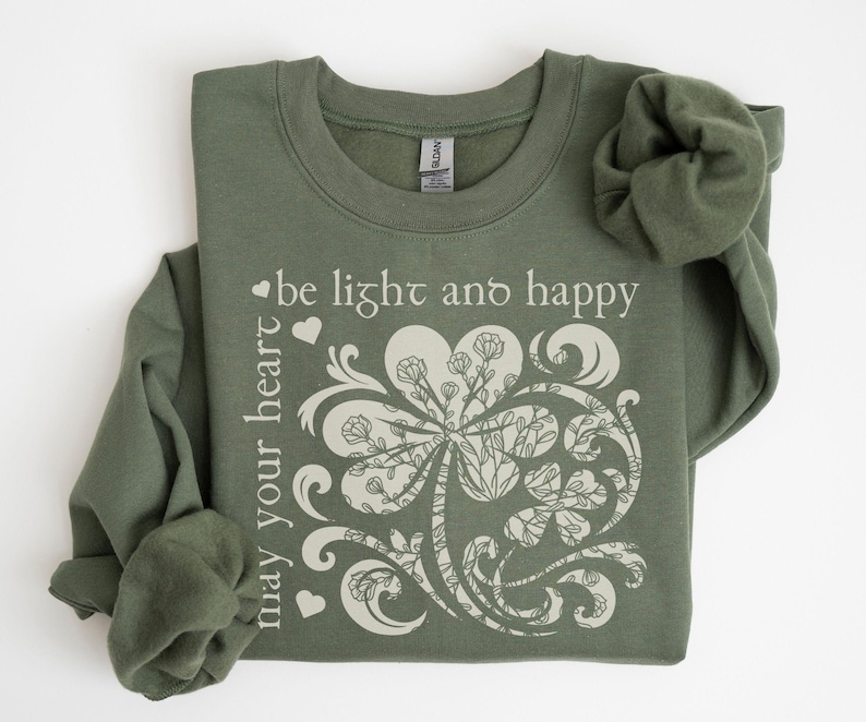 May include: A green sweatshirt with a white clover design and the text "may your heart be light and happy".