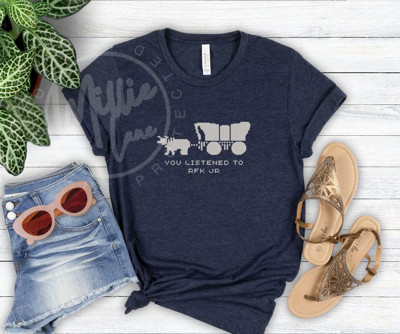 Puede incluir: Camiseta azul marino con un gr&aacute;fico de una carreta cubierta tirada por un oso, con el texto "YOU LISTENED TO RFK JR" en blanco. La camiseta se combina con pantalones cortos de mezclilla y gafas de sol.