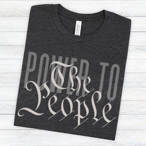 May include: A dark heather grey t-shirt with the text "Power to the People" printed in white on the front.