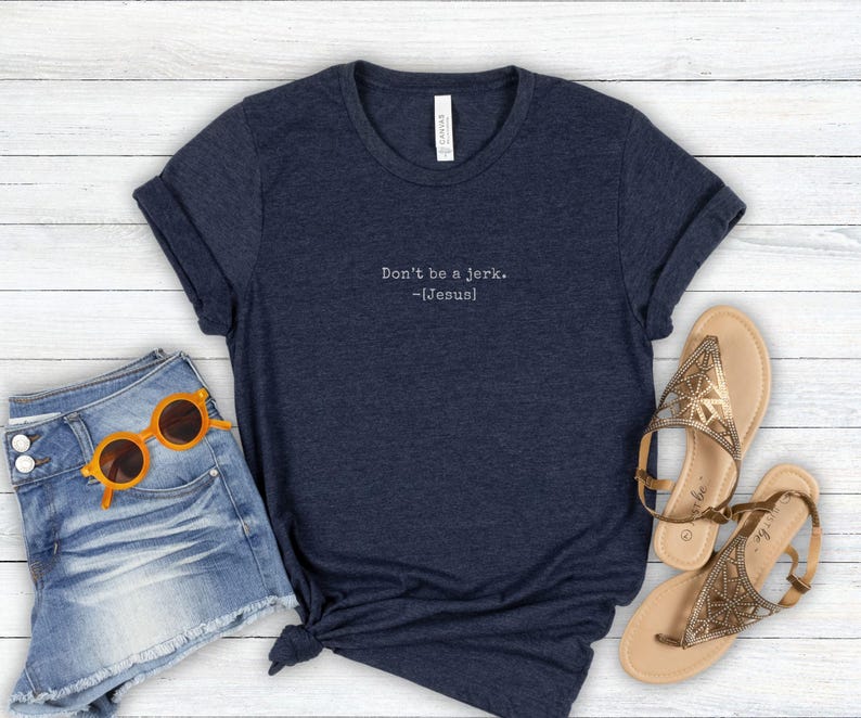 Peut inclure: T-shirt bleu marine avec l'inscription blanche "Don't be a jerk. -[Jesus]" . Le t-shirt est associ&eacute; &agrave; un short en jean, des lunettes de soleil orange et des sandales dor&eacute;es.