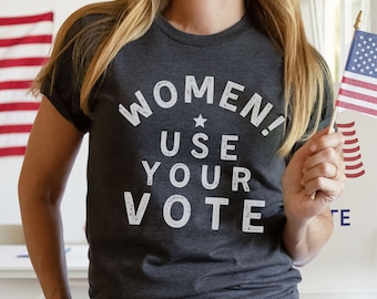 May include: A dark grey t-shirt with a white distressed graphic that reads "Women! Use Your Vote" and a small white star.
