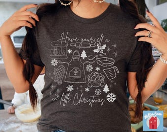 Könnte beinhalten: Ein dunkelgraues T-Shirt mit einem weißen Design, das verschiedene Küchenutensilien und den Text "Have yourself a little Christmas" zeigt.